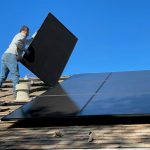 Solar Panels - man in white dress shirt and blue denim jeans sitting on white and black solar panel