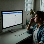 Mortgage Application - man in blue denim jacket facing turned on monitor