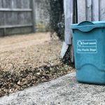 Compost Bin - green trash can beside wooden fence