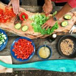 Outdoor Kitchen - person slicing green vegetable in front of round ceramic plates with assorted sliced vegetables during daytime