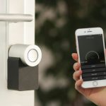 Smart Home Security - gold Apple iPhone smartphone held at the door