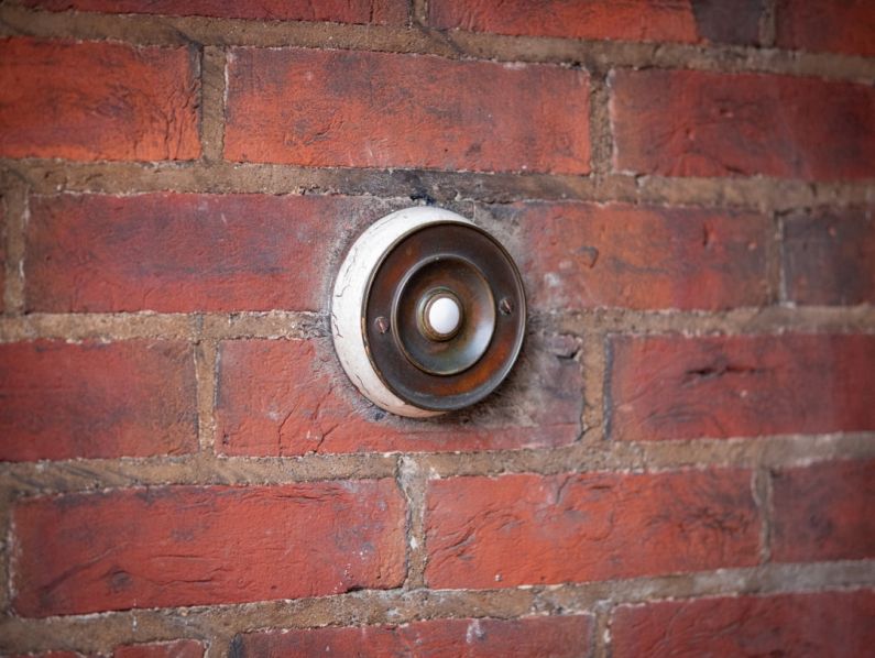 Doorbell - brown and black round metal on brown brick wall