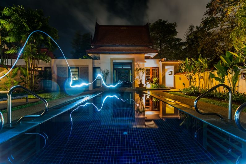 Smart Home - reflection of blue light crossing above pool near house during nighttime