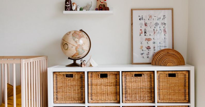 Children Design - Comfortable bed with toys globe and paintings placed on wooden cabinet with wicker boxes and soft white rug with toy house on floor